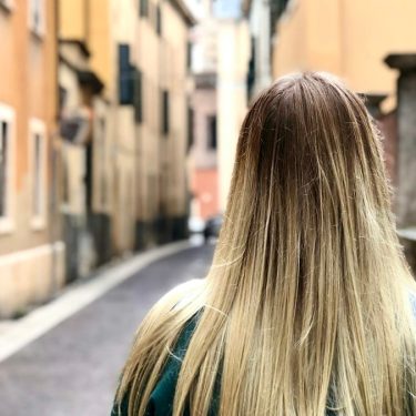 a woman with long blonde hair walking down a street